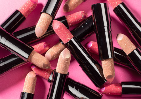 Mehrere Lip Jewels von Artdeco liegen auf einem pinken Hintergrund